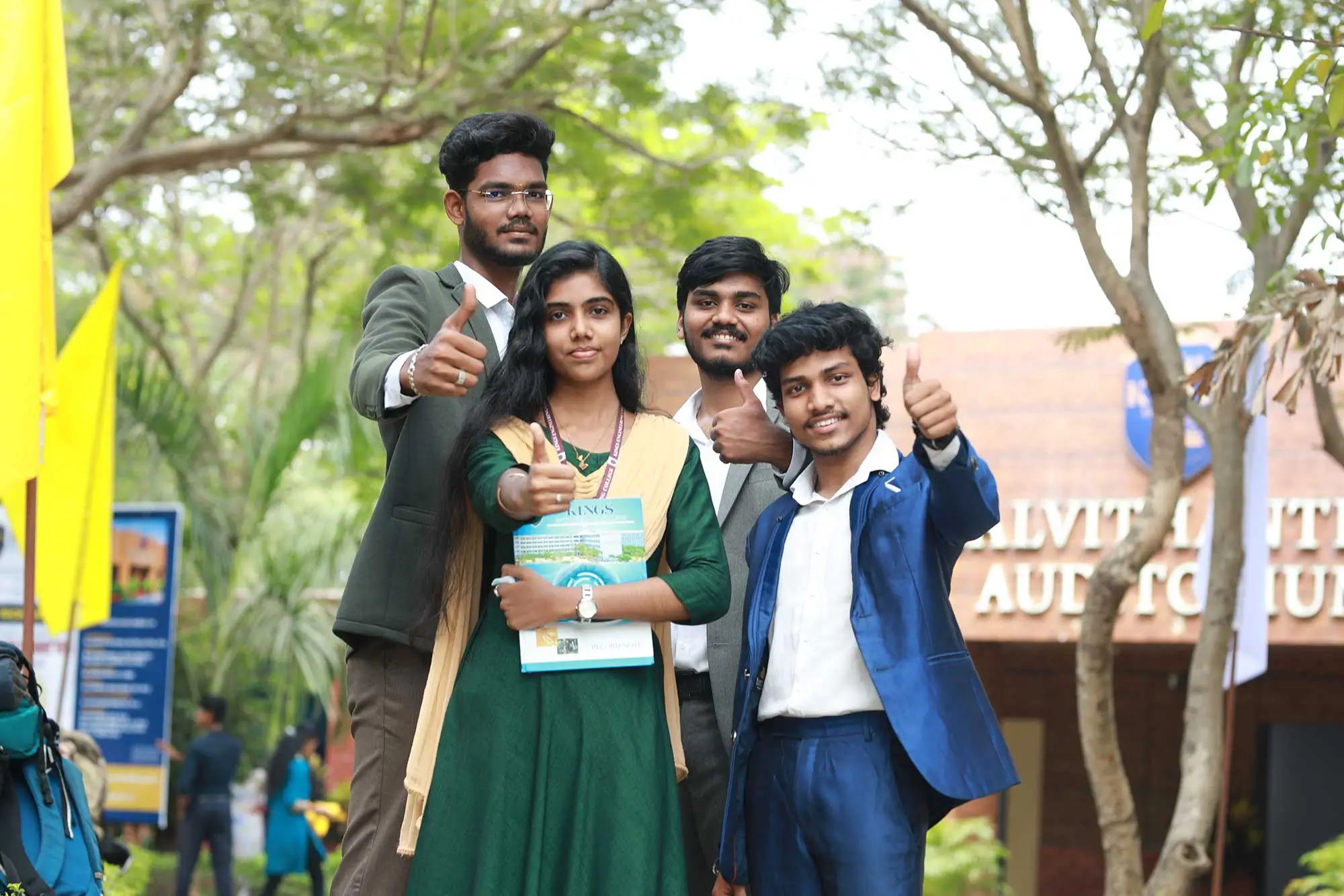 four students showing thumbs up